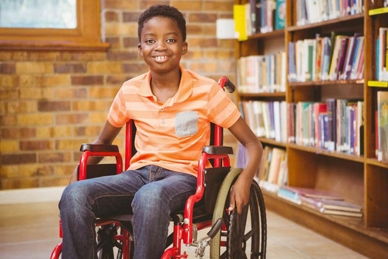 A boy in a wheelchair in a library.