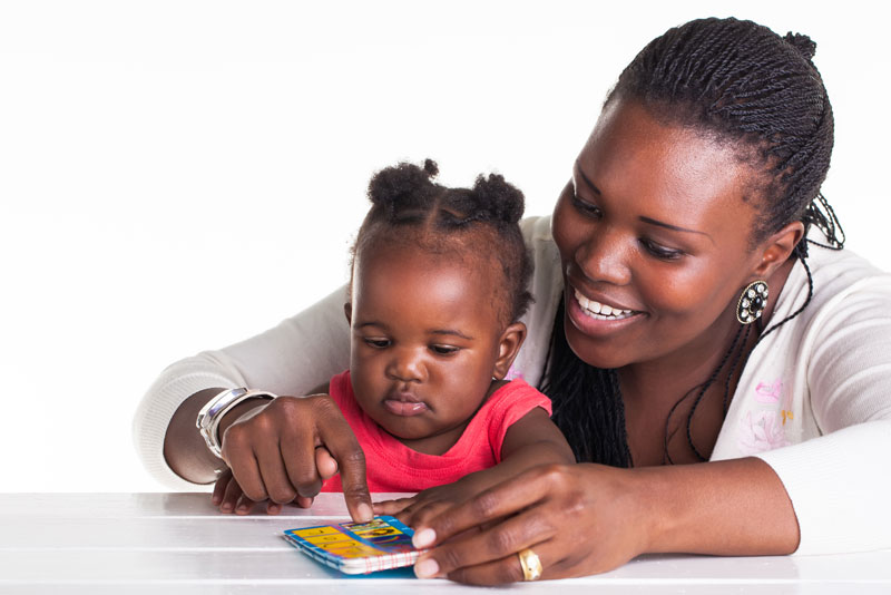 A mother and child playing with a cell phone.