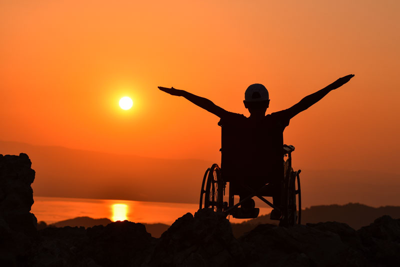 a man on a wheelchair watching sun set