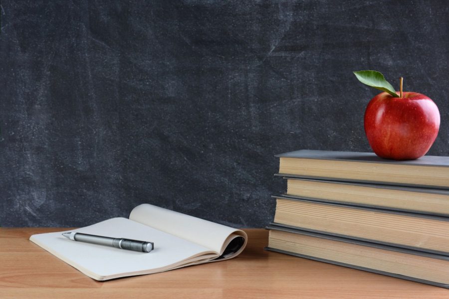 an open notebook and an apple on the book stack